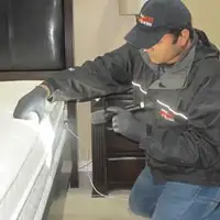 Bed bug inspection technician checking a mattress and bed frame for signs of infestation in Columbia, MO