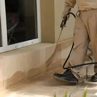 General pest control technician spraying exterior perimeter around a home in Columbia, MO