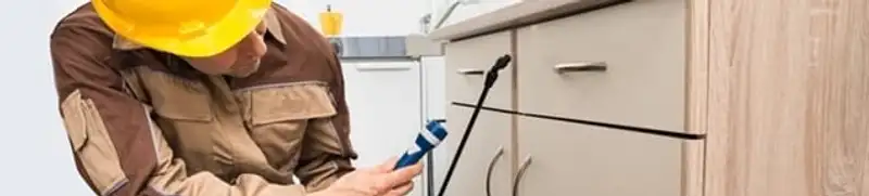 Roach exterminator applying treatment under kitchen cabinets in Columbia, MO