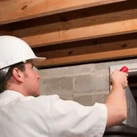 Termite inspection technician checking a basement wall and framing for termite activity in Columbia, MO