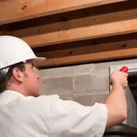Termite inspection technician checking a basement wall and framing for termite activity in Columbia, MO
